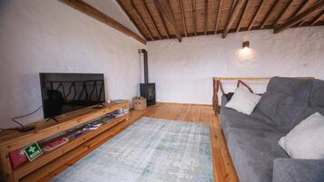 Ein gemütliches Wohnzimmer mit Fernseher, Holzschrank, Sofa und Kamin.