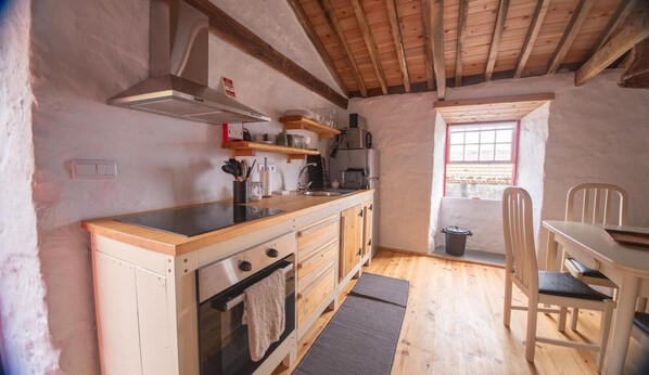 A compact kitchen with wooden cabinets, a built-in oven, and a dining area with a table and chairs.