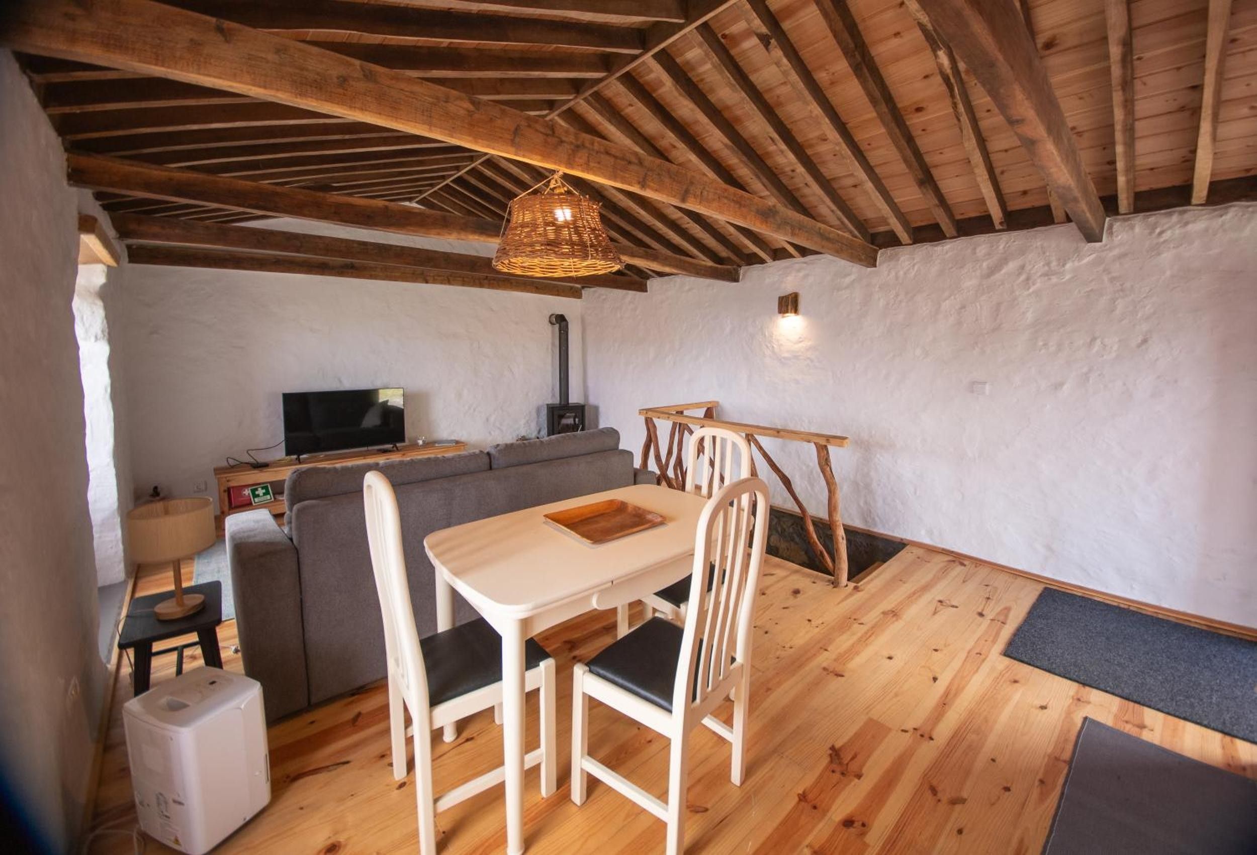 A cozy room with a wooden ceiling, a dining table with chairs, a sofa, a television, and a fireplace.