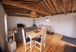 Una habitación acogedora con techo de madera, una mesa de comedor con sillas, un sofá, un televisor y una chimenea.
