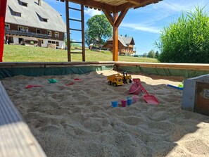 Ein Sandspielbereich mit Spielzeug und einer Holzkonstruktion.