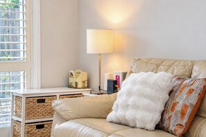 Uma sala de estar acolhedora com um sofá de couro, uma luminária e uma mesa pequena com um cesto.