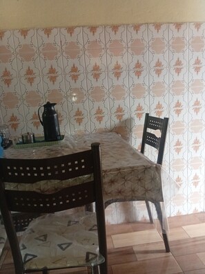 A dining area with a table covered by a patterned tablecloth, two chairs with a geometric design, and a black pitcher on the table. - House with pool for your family retreat, rest and leisure. (Belém)
