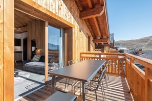 Une terrasse en bois avec une table et des chaises, un canapé et un coin cuisine avec une fenêtre.