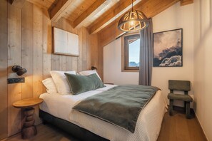 Une chambre à coucher aux murs lambrissés, avec un lit, une table de chevet et un luminaire suspendu.