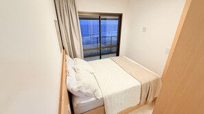 Ein kleines Zimmer mit einem Einzelbett und einem Fenster mit Blick auf ein Gewässer.