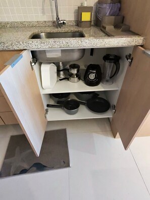 Una cocina con encimera de granito, pileta de acero inoxidable y un mueble de almacenamiento empotrado.