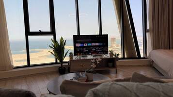 A modern living room with a large window, a flat-screen TV, a coffee table, and a sofa.