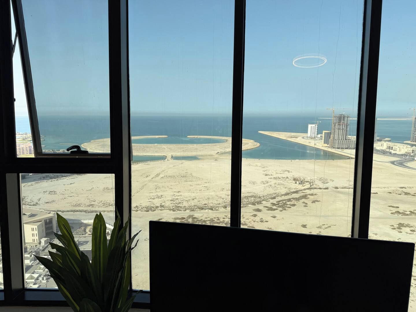 A view from a window overlooking a coastal area with sandy beaches, a marina, and several high-rise buildings.
