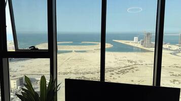 A view from a window overlooking a coastal area with sandy beaches, a marina, and several high-rise buildings.