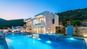 A modern two-story house with a swimming pool, outdoor seating, and a view of a hillside. - Vrbo Property (Kalkan)