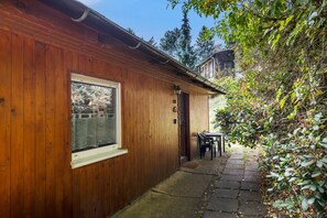 Ein Holthaus mit Fenster, einer Tür und einem kleinen Tisch mit Stühlen davor.