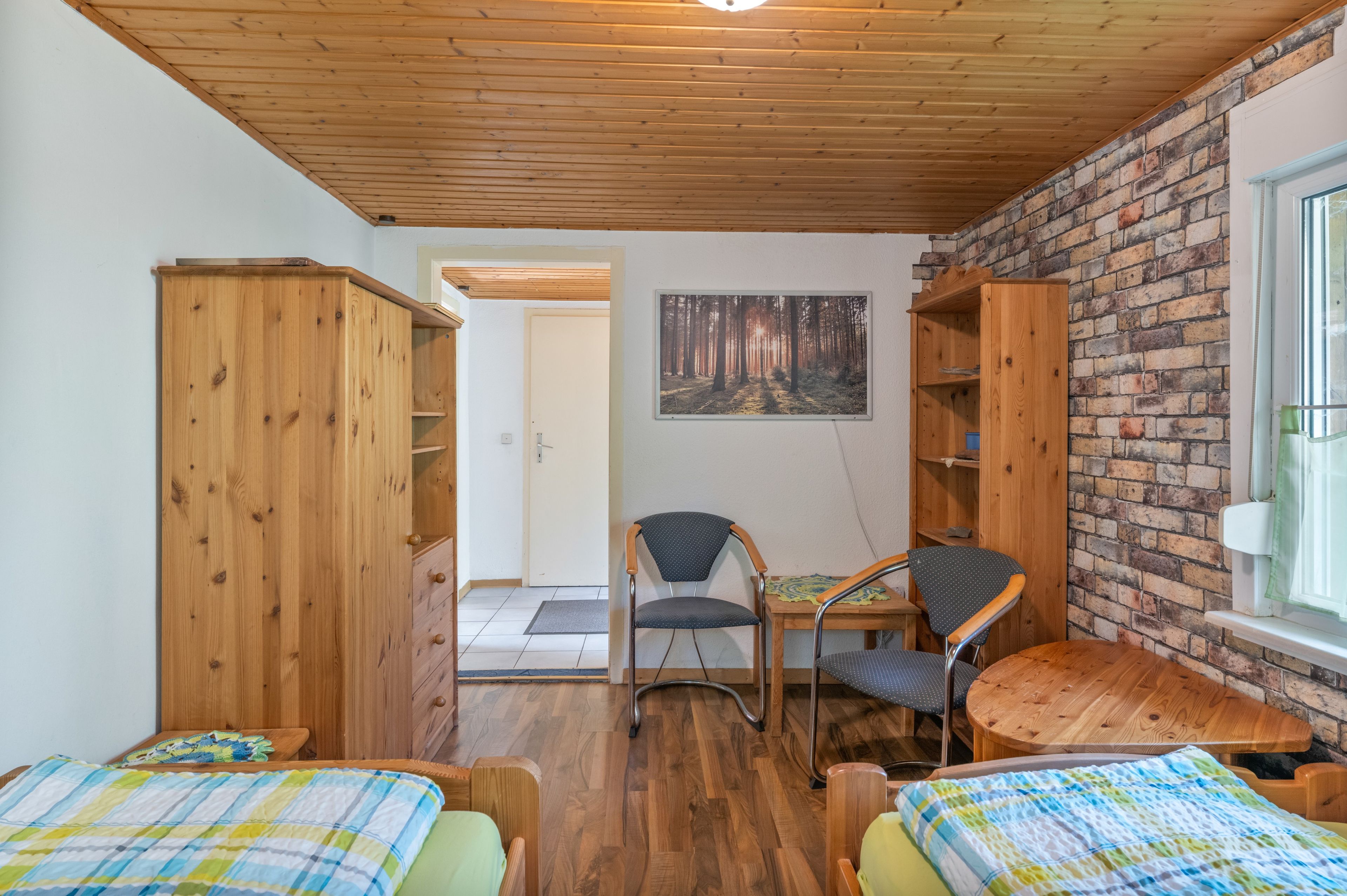 Ein Zimmer mit Holzmöbeln, einer Ziegelwand und einem Bild von einem Wald.