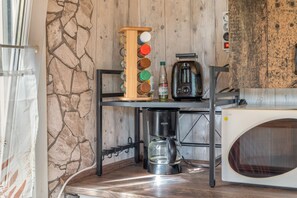 A kitchen with a stone wall, a wooden spice rack, a coffee maker, and a microwave.
