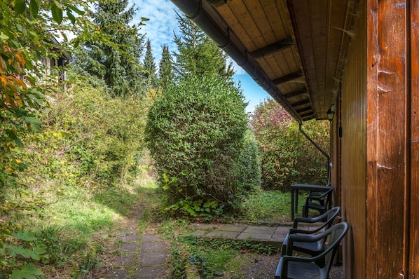 A covered outdoor area with a wooden structure, a paved path, and a bench.