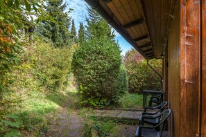 A covered outdoor area with a wooden structure, a paved path, and a bench.