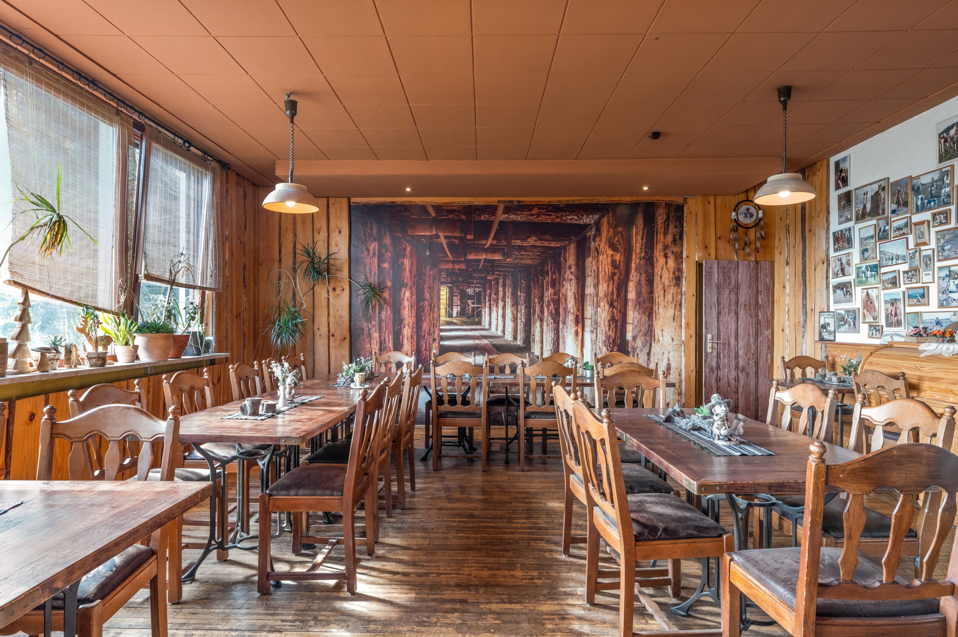 Ein Restaurant mit Holzvertäfelungen, langen Tischen und Stühlen.