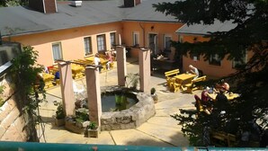 Un espacio al aire libre con mesas y sillas, una pequeña fuente de agua y un edificio con varias ventanas.