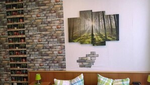 Een kamer met een bakstenen muur, een bed met groene beddengoed en een wandplank met plantenpotten.