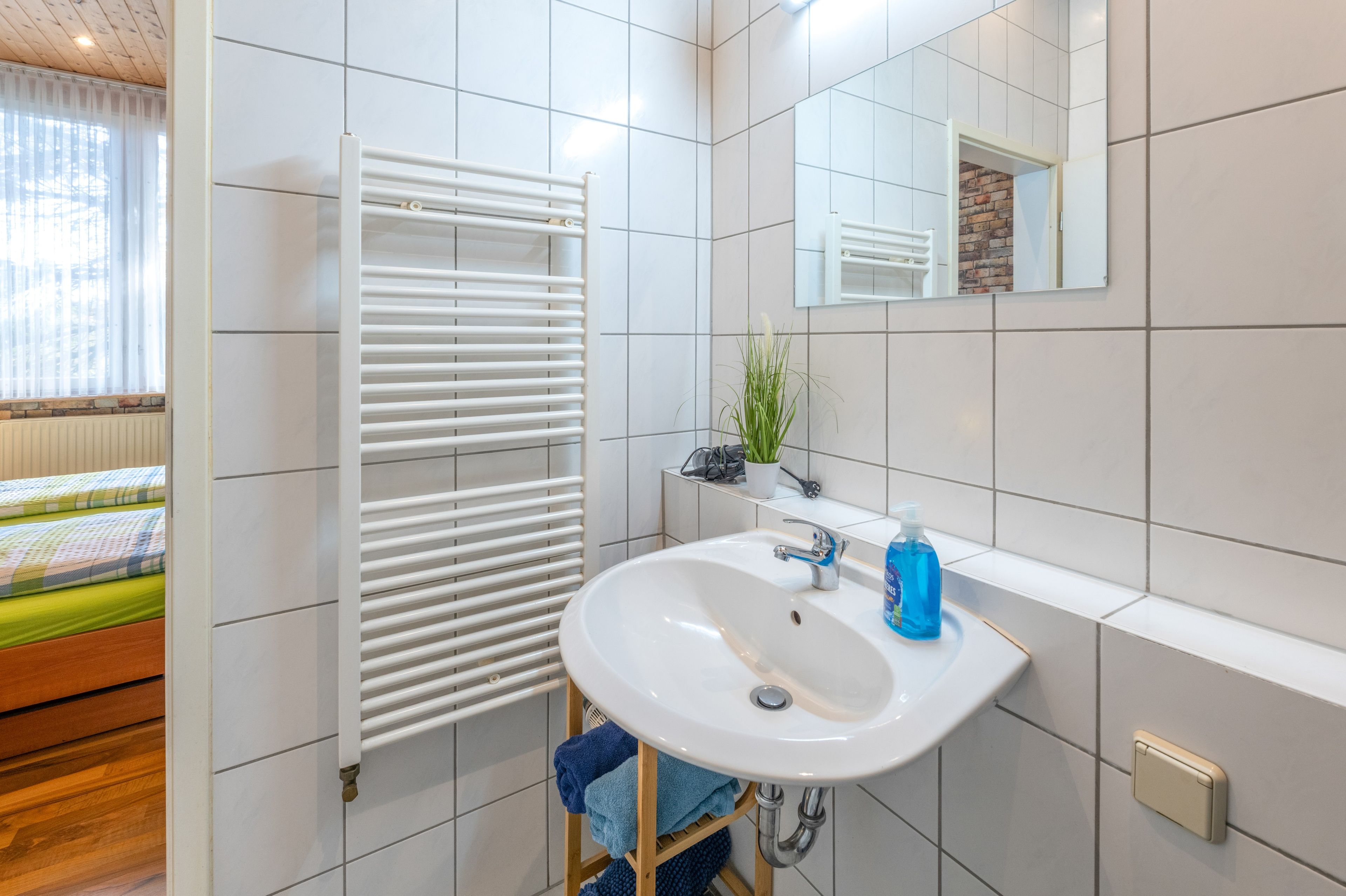 Een moderne badkamer met een wit wastafelmeubel, een spiegel en een handdoekrek.