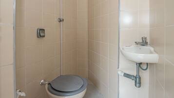 Une petite salle de bain carrelée, équipée de toilettes et d’un lavabo.