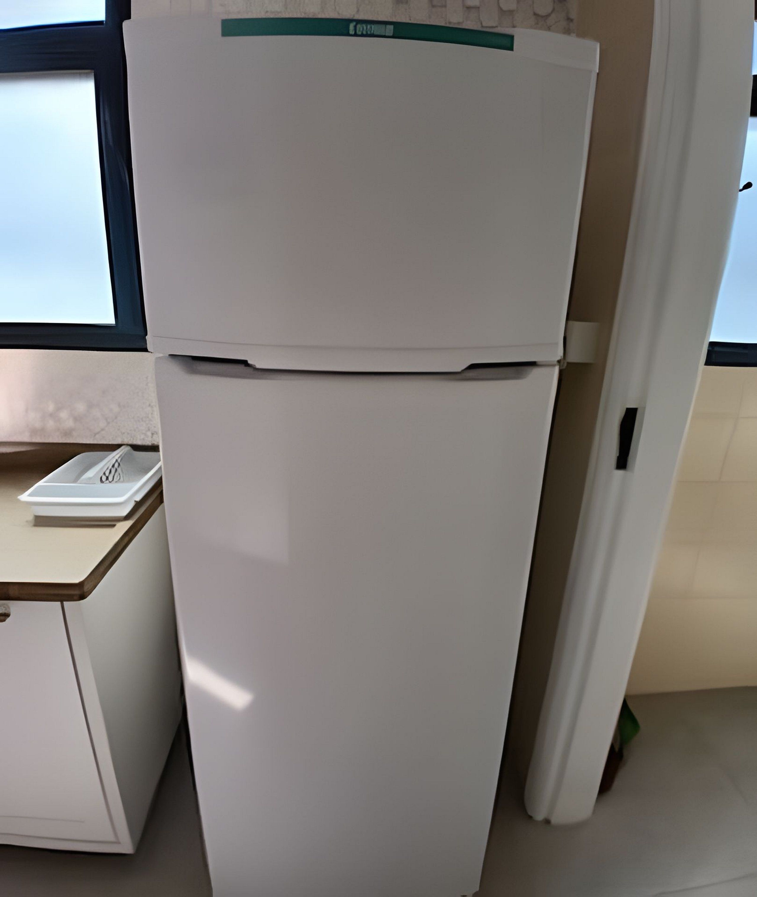 A white refrigerator with a green label in a kitchen.