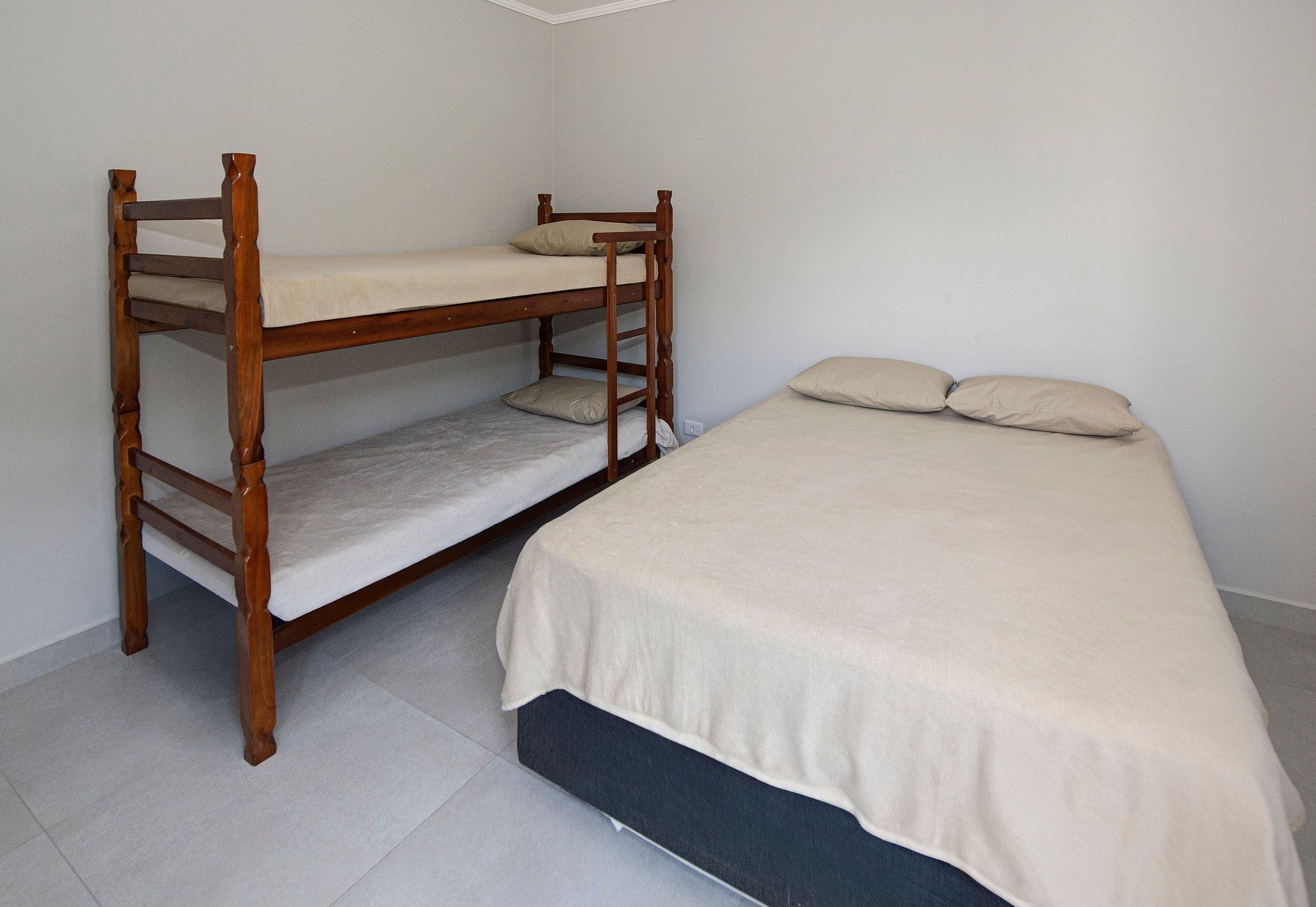 A bunk bed with a lower bunk and a single bed with a mattress and pillows.