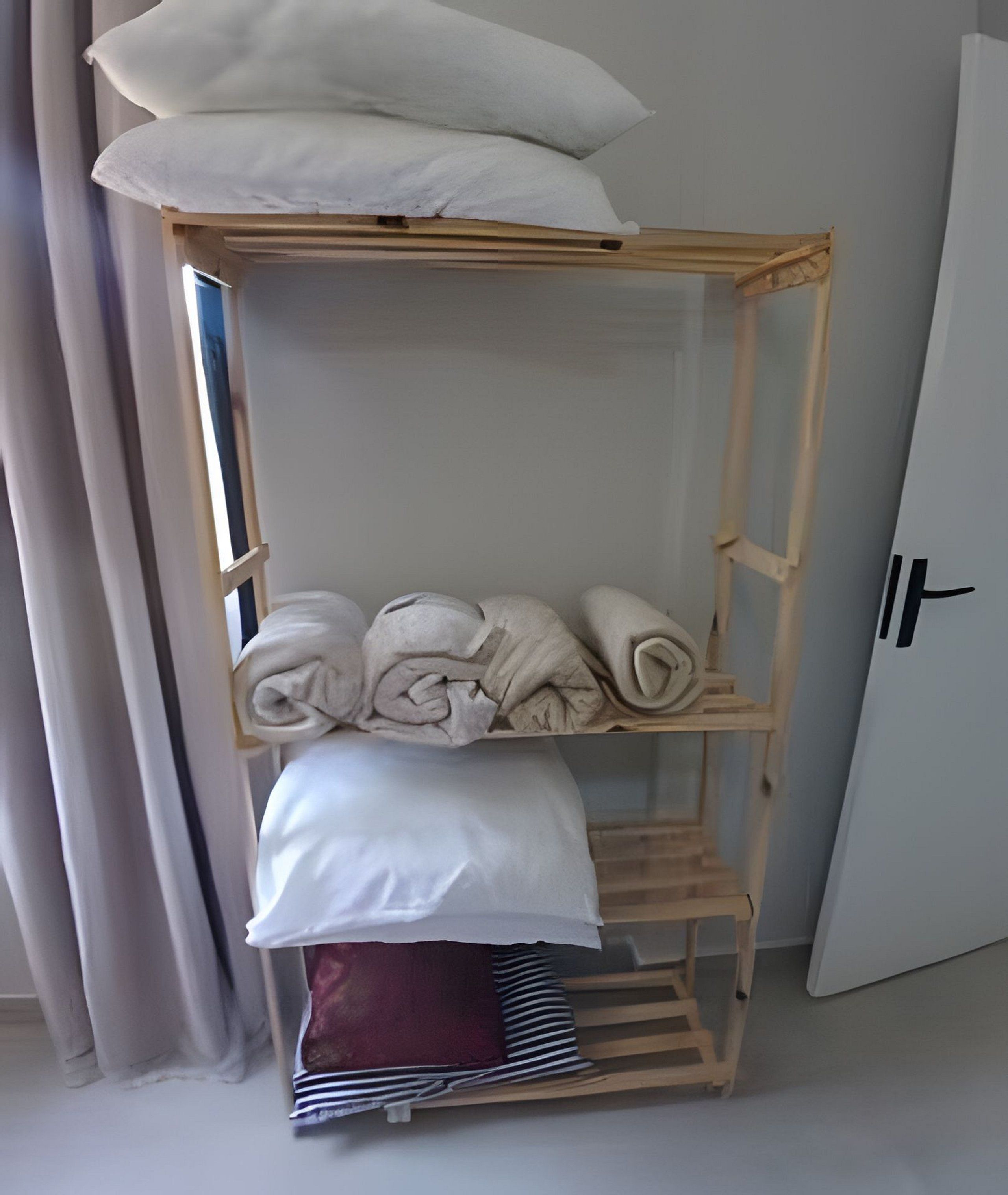 A wooden shelf unit with towels and a folded blanket.