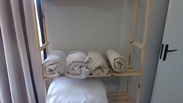 A wooden shelf unit with towels and a folded blanket.