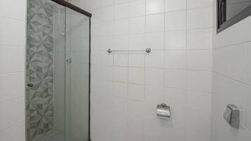 A bathroom with a glass shower enclosure, white tiled walls, and a towel rack.