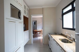 A kitchen with white cabinets, a wooden dining table, and a window.