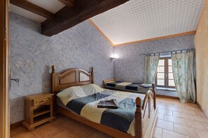Een slaapkamer met een houten bed, een nachtkastje, een raam met gordijnen en een gestructureerd plafond.