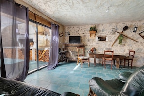 Ein rustikales Interieur mit einer Steinwand, Holzmöbeln und einem großen Fenster mit Vorhängen.