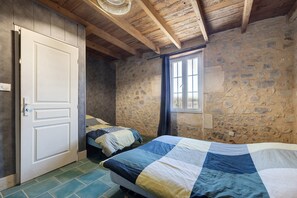 A bedroom with a stone wall, a wooden ceiling, a window, and a door. - Charming Winegrower's House with Lake View, Private Pool, and Wi-Fi (Guizengeard)