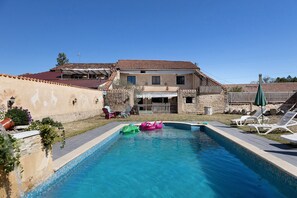 A swimming pool with inflatable toys, a patio with lounge chairs, and a house with a tiled roof. - Charming Winegrower's House with Lake View, Private Pool, and Wi-Fi (Guizengeard)