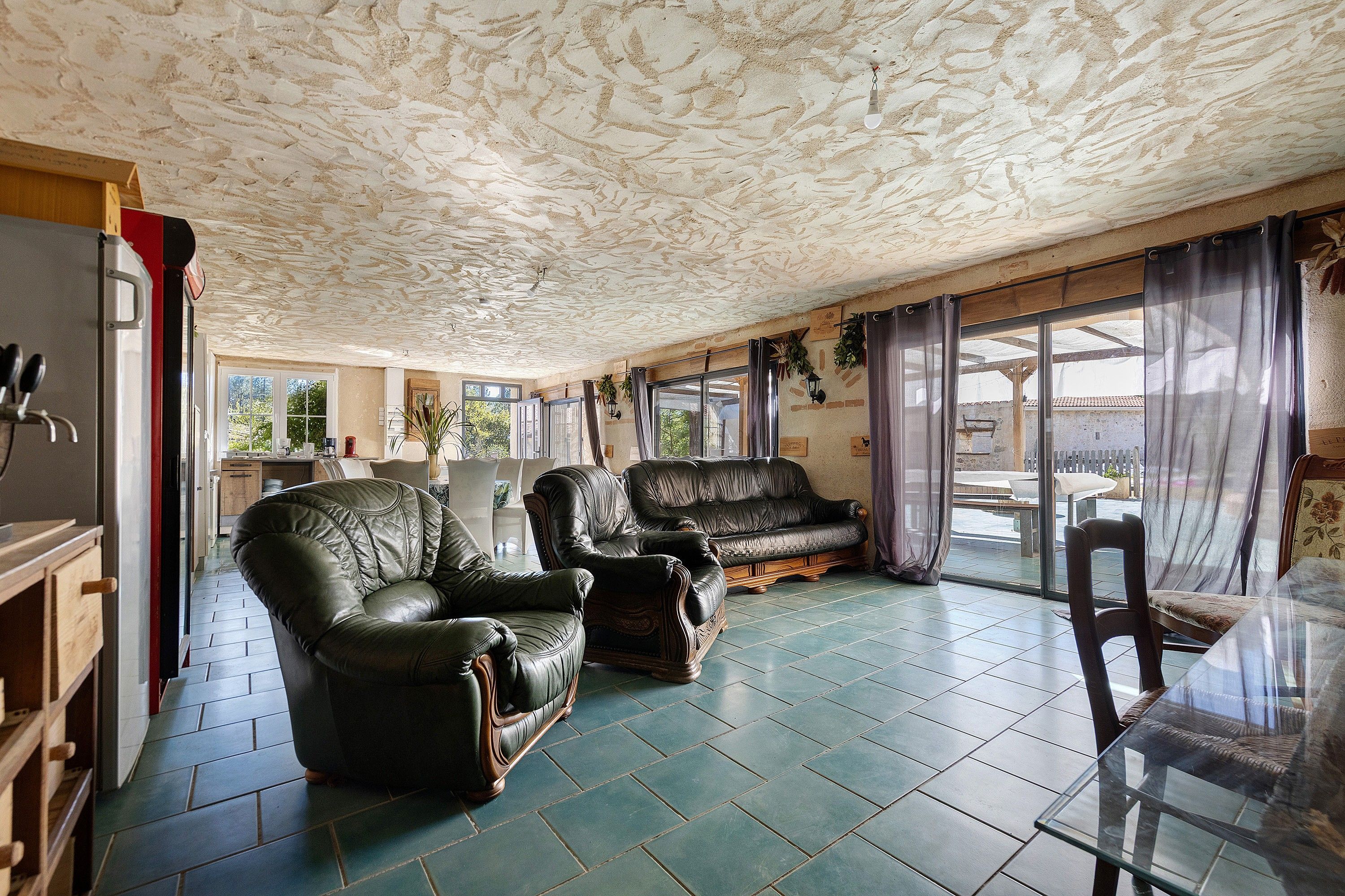 A spacious living area with a large sofa, a smaller armchair, and a glass table.