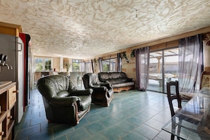 A spacious living area with a large sofa, a smaller armchair, and a glass table. - Charming Winegrower's House with Lake View, Private Pool, and Wi-Fi (Guizengeard)