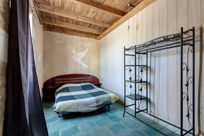 A bedroom with a bed, a wardrobe, and a metal shelf unit. - Charming Winegrower's House with Lake View, Private Pool, and Wi-Fi (Guizengeard)