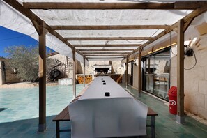 An outdoor covered area with a long table, wooden beams, and a stone wall. - Charming Winegrower's House with Lake View, Private Pool, and Wi-Fi (Guizengeard)