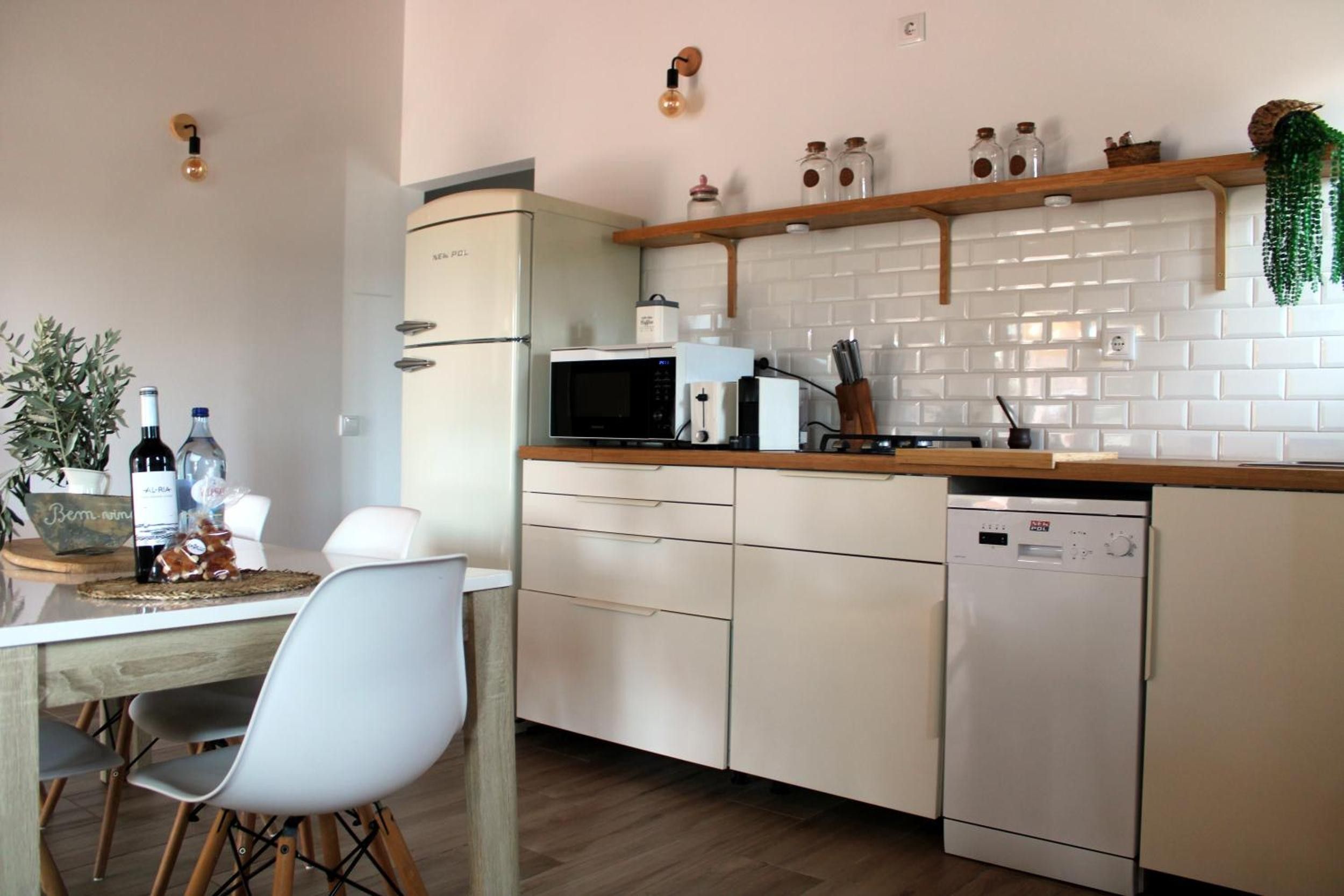 Una cucina compatta con frigorifero, forno a microonde ed elettrodomestici. C'è un tavolo da pranzo con sedie e una pianta in vaso sul tavolo.