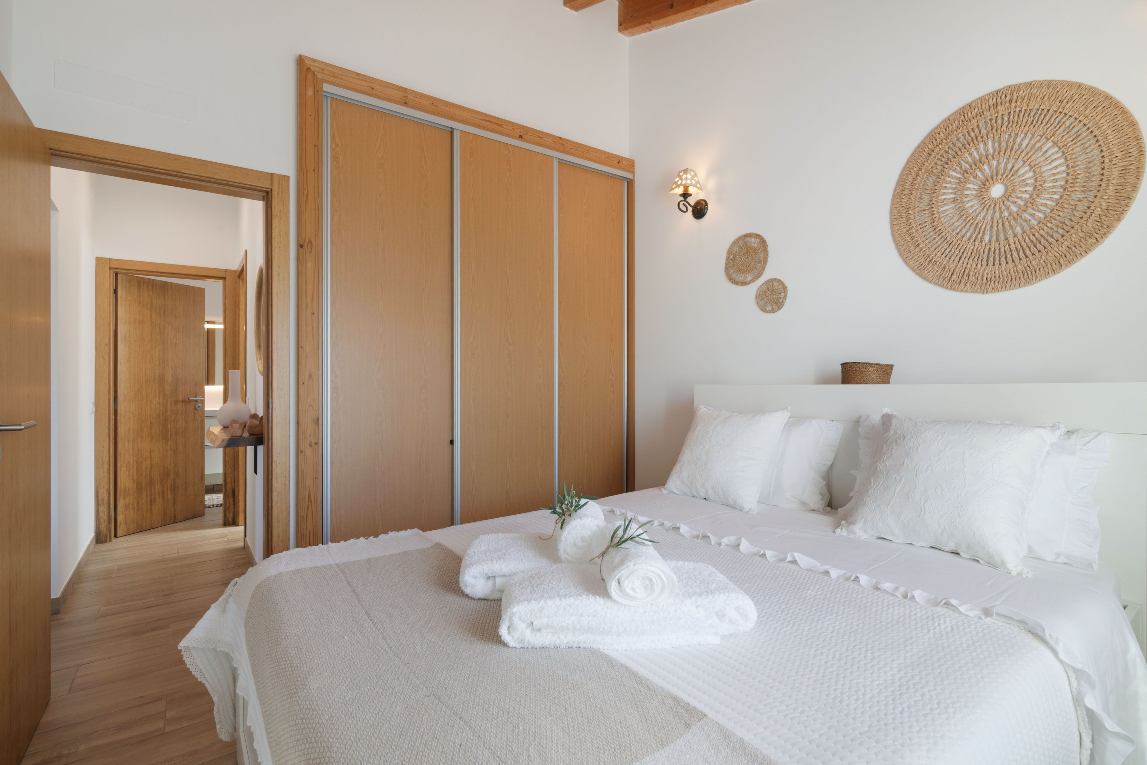 Quarto com uma cama grande, guarda-roupa de madeira e um cesto trançado fixado na parede.