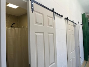Une porte coulissante avec un rail en métal, un rideau de douche et une porte verte.
