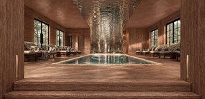 A long, narrow indoor pool with a clear view of the sky through large windows, surrounded by seating areas with cushioned chairs. - Maison Limelette (Ottignies-Louvain-la-Neuve)