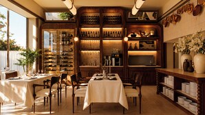 A restaurant with a long dining table, chairs, and a wine rack with bottles. - Maison Limelette (Ottignies-Louvain-la-Neuve)