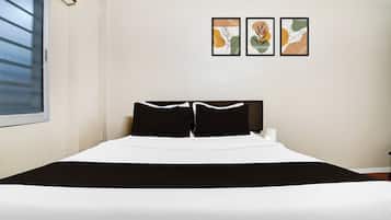 A bed with a black and white bedspread, two black pillows, and a headboard. There are three framed artworks on the wall above the bed.