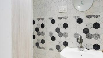A bathroom with a white sink, a mirror, and a hexagonal patterned wall.