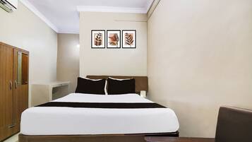 Una habitación de hotel con una cama, un escritorio, un armario y tres cuadros en la pared.