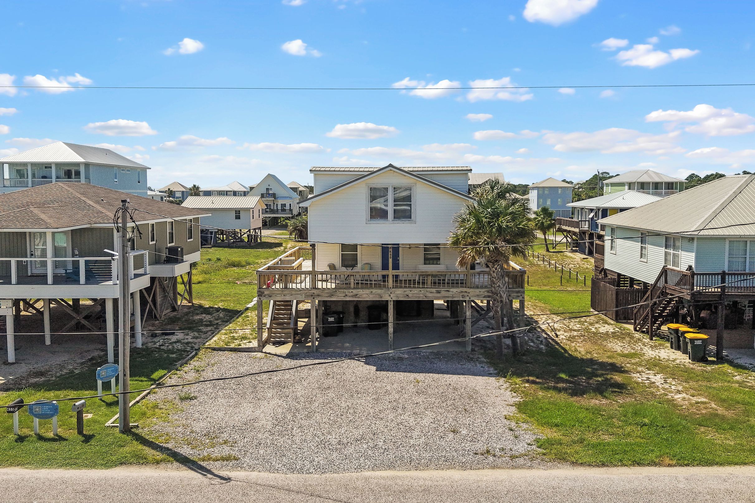 A beachfront property with a central house featuring a deck, surrounded by other houses with similar architecture.