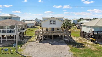 A beachfront property with a central house featuring a deck, surrounded by other houses with similar architecture.