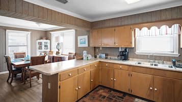 A kitchen with wooden cabinets, a dining area with a table and chairs, and a kitchen island with a sink and appliances.